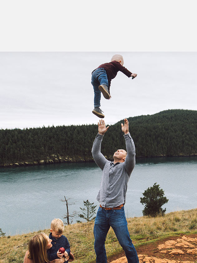 Father throwing toddler in the air by a lake