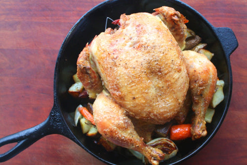 roasted whole chicken in pot with veggies