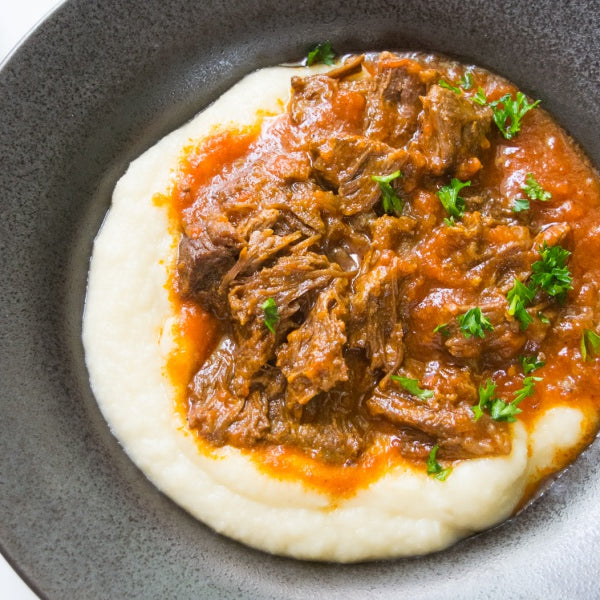slow cooked beef cheeks in dish with potatoes