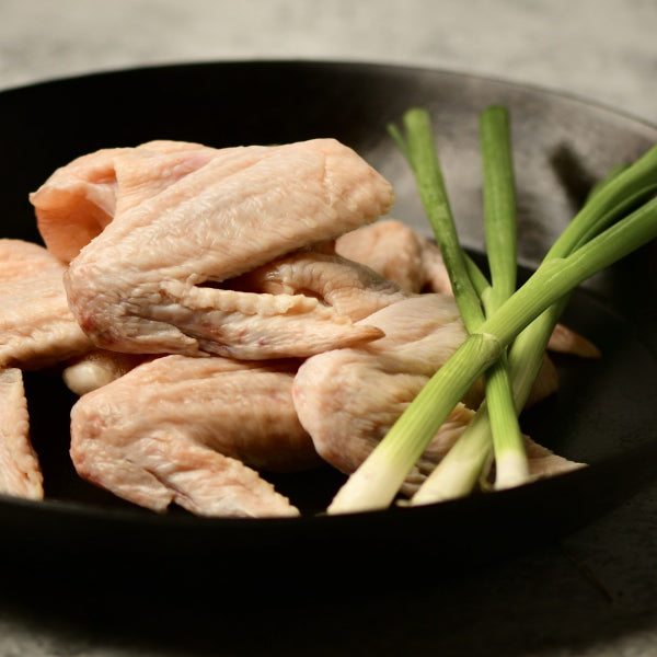 pasture raised chicken wings in skillet with onions