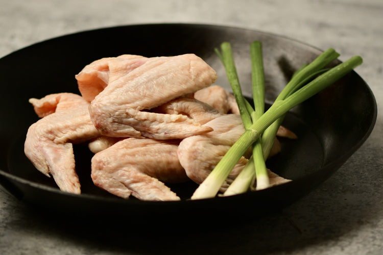 pasture raised chicken wings in skillet with onions