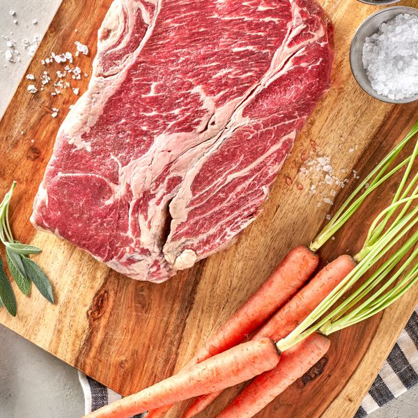 grassfed beef chuck roast on cutting board with carrots and potatoes