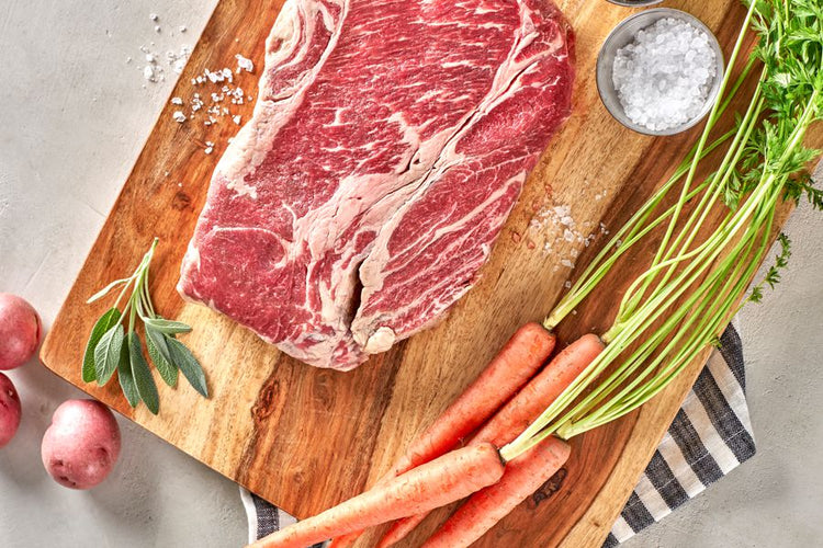 grassfed beef chuck roast on cutting board with carrots and potatoes