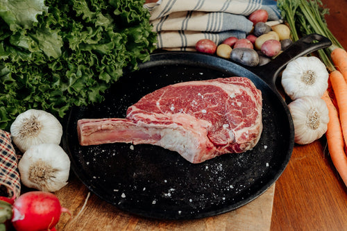 grass-fed beef french cut, bone-in ribeye on a plate salted