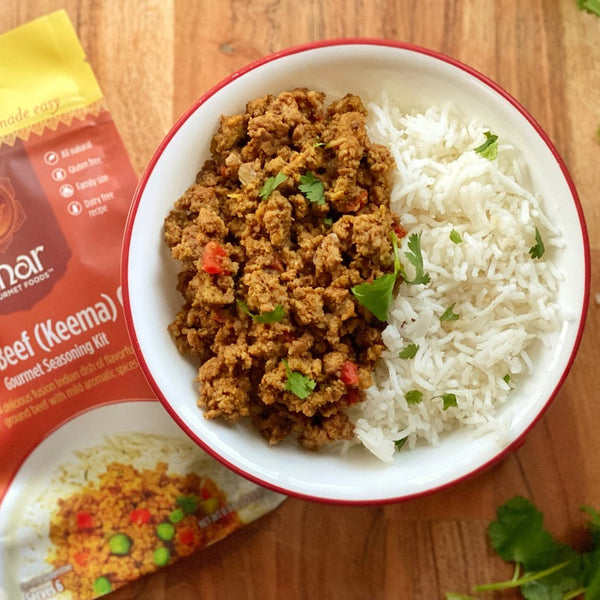  bowl of ground beef keema with rice next to anar brand seasoning packet on a wooden surface