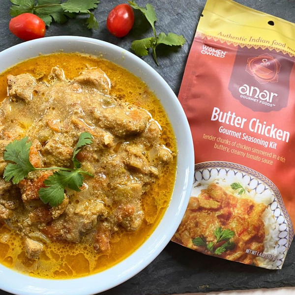 Butter Chicken dish with a package of anor Gourmet Foods Butter Chicken seasoning kit.