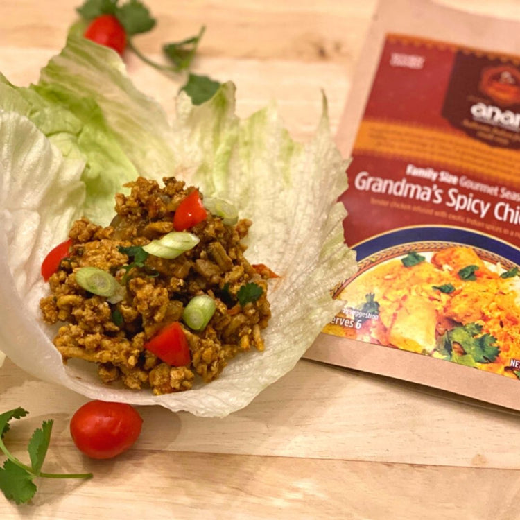 Lettuce wrap with ground meat and vegetables on a wooden surface beside a package of Anas family sun gourmet seasoning.
