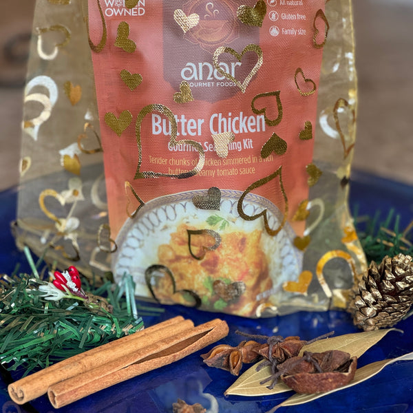 Anar Butter Chicken seasoning kit on a blue plate with spices and a cinnamon stick.