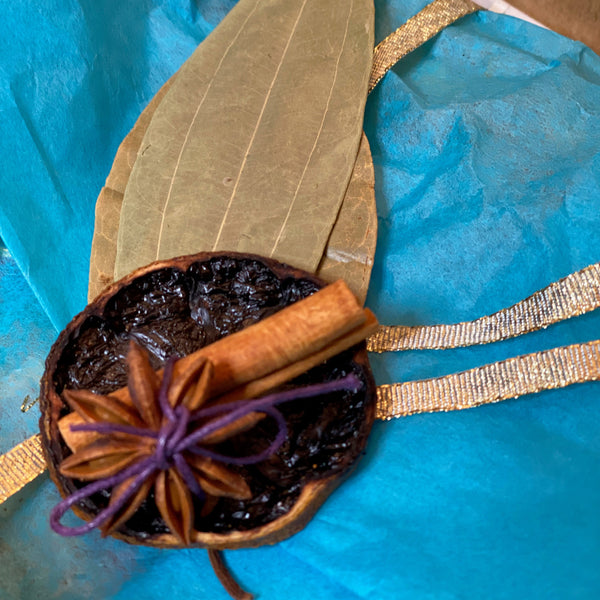 Spice bundle with cinnamon stick, star anise, and bay leaf on blue tissue paper.