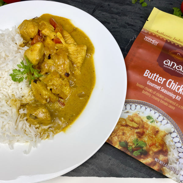 Butter Chicken dish with rice on a white plate next to an Anar Gourmet Seasoning Kit packaging.