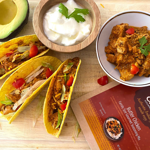 Tacos with chicken, avocado, and yogurt on a wooden surface with an Enar Butter Chicken package.
