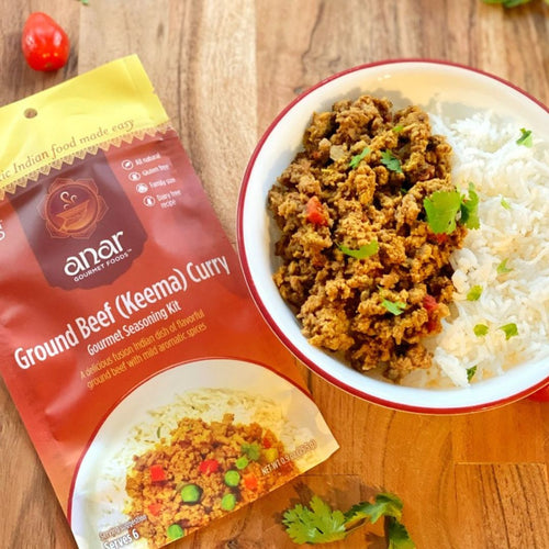 Anar Ground Beef Keema Curry seasoning kit beside a bowl of ground beef and rice on a wooden surface.