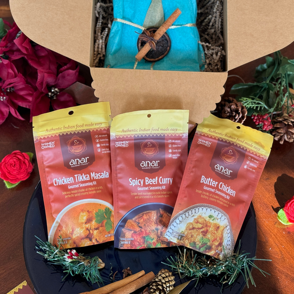Three packets of anar Indian food seasoning kits on a dark surface with decorative elements.
