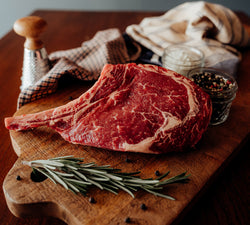 Raw Beef French Ribeye Steak on a chopping board with herbs