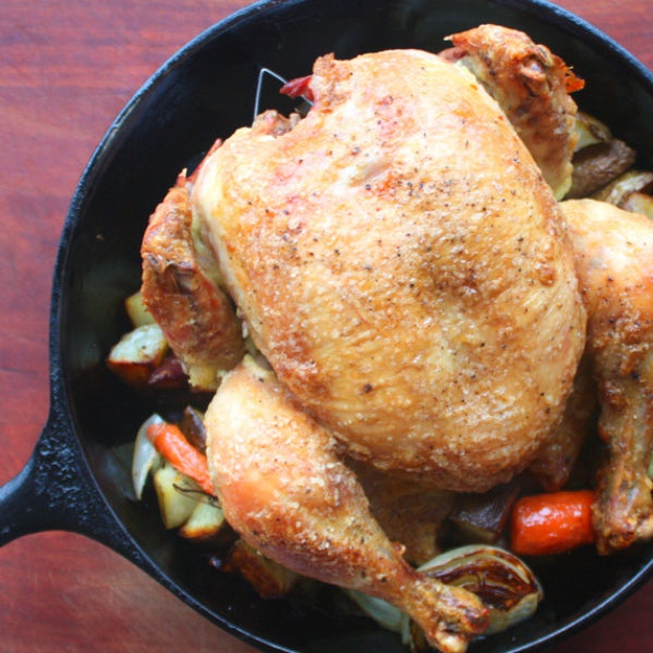 roasted whole chicken in pot with veggies
