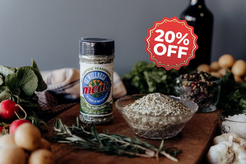 All Purpose USWM Spice jar with a 20% off label on a wooden board with herbs and vegetables.