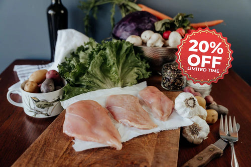 Raw chicken breasts on a wooden cutting board with vegetables and a '20% off' promotion sign.