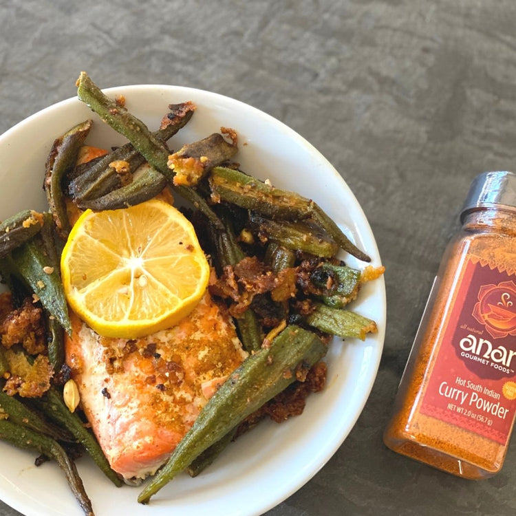 Bowl of food with okra and lemon slice, next to a bottle of Anar Curry Powder.