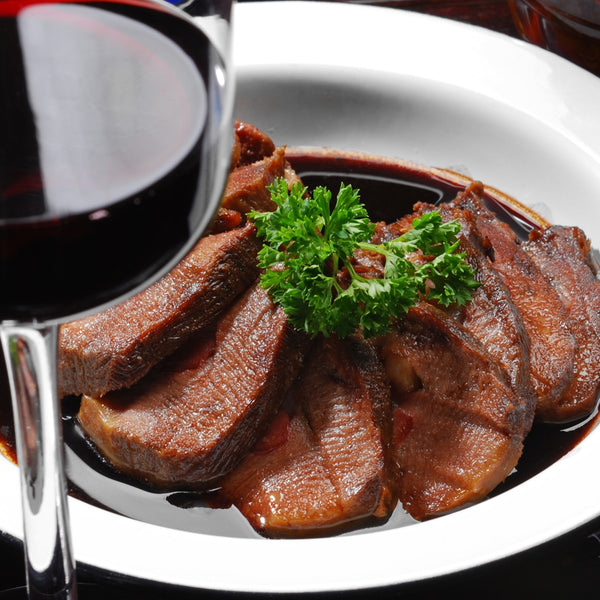 bison tongue sliced on plate with garnish, gourmet meal with wine