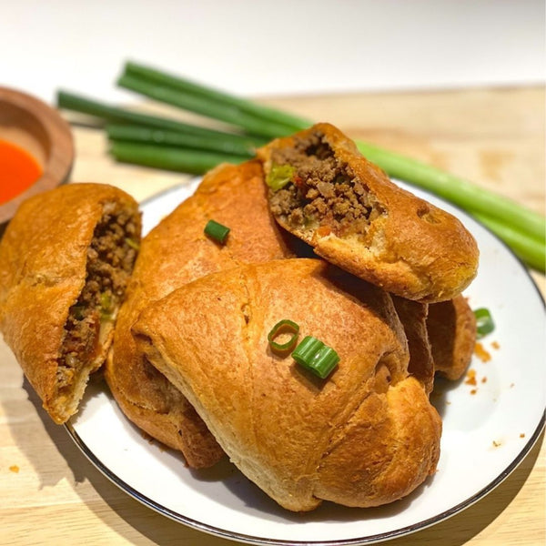 Baked pastries with green onions on a plate with a side of dipping sauce.
