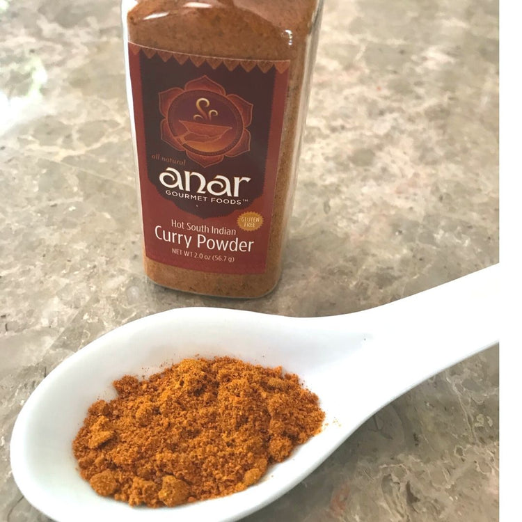 Anar Gourmet Foods Hot South Indian Curry Powder bottle with a spoonful of powder on a marble surface