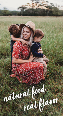 Photo of a mother with her two children in a grass field