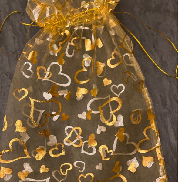 Translucent gold and silver heart-patterned bag on a dark background