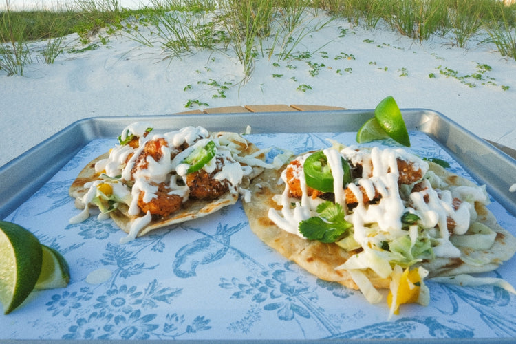 Wild-caught Shrimp Tacos with toppings on a tray by the beach