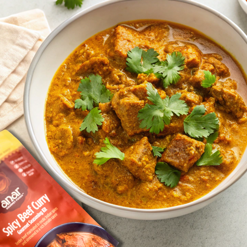 Spicy beef curry in a bowl with a packet of Amar Spicy Beef Curry seasoning mix.