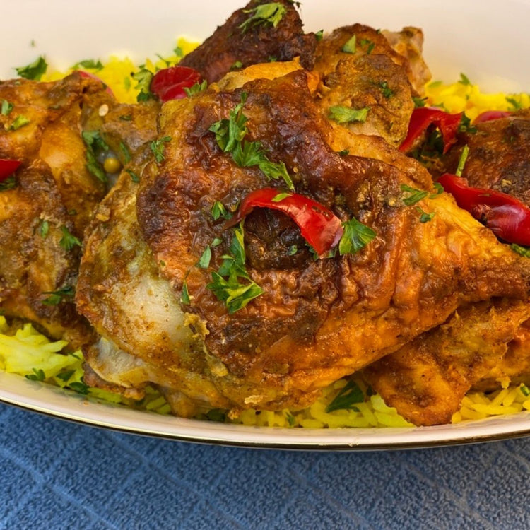 Plated dish of roasted chicken with vegetables on a blue textured surface