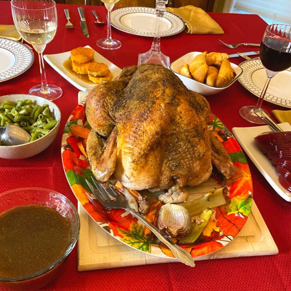 Roasted turkey on a festive table setting with sides and drinks.