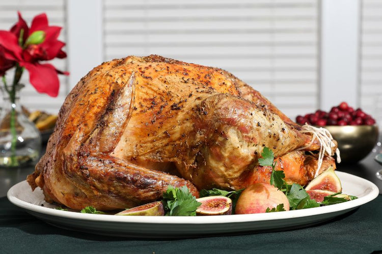 Roasted turkey on a platter with figs and greens, set against a festive background.